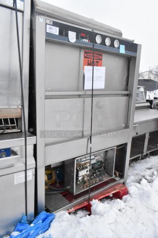 Douglas Commercial Front Load Pot and Pan Washer, stainless steel, visible "HOT" warning label, open wiring panel, snow-covered.