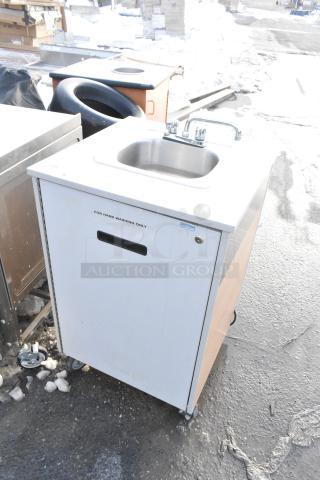 Portable sink on casters with instant flow water heater. Stainless steel basin, labeled for hand washing only. Clean condition.