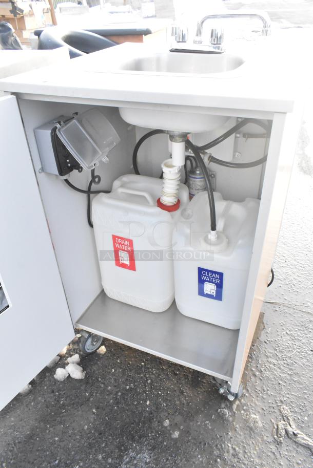 Portable sink on casters with instant flow water heater, featuring labeled drain and clean water containers. In good condition.
