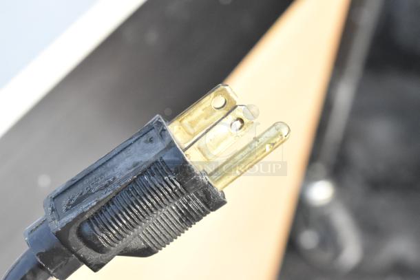 Close-up of an electrical plug, likely part of the Portable Sink on Casters with Instant Flow Water Heater, highlighting the plug's prongs and condition.