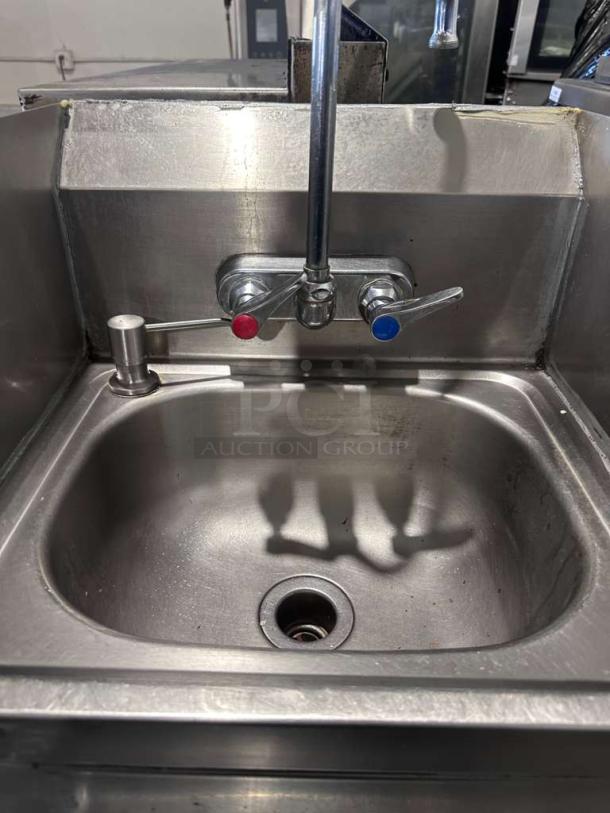 Commercial stainless steel hand wash sink with gooseneck faucet, built-in paper towel dispenser, high-grade condition.