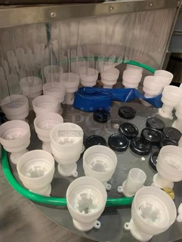 Rotary round bottle washer by Tang, showing holders and parts for bottle rinsing. Used condition, fully operational.
