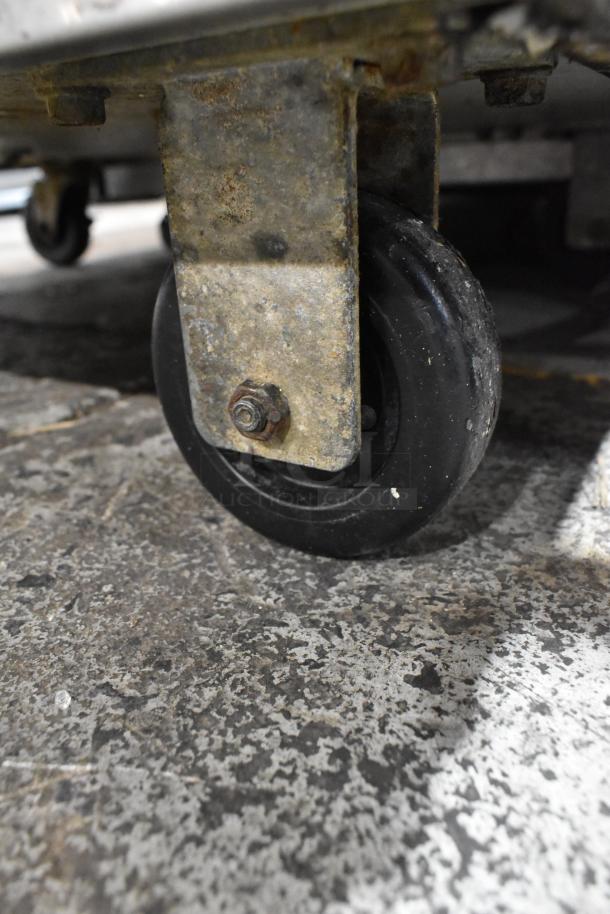 Rusty caster wheel of Carpigiani LB-502 batch freezer on a rough concrete floor, showing condition of the unit's base.