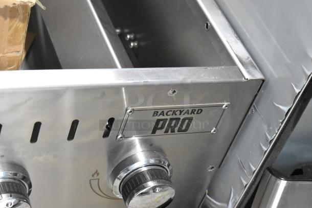 Brand new Backyard Pro propane grill, floor style, with visible scratches and dents, stainless steel construction.