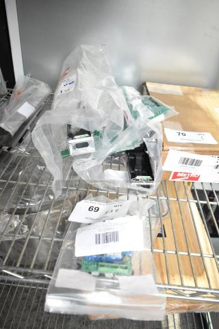 Four brand new control boards, scratch and dent, in clear plastic bags with visible labels on metal shelving.