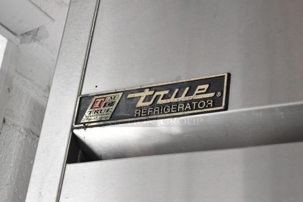 True TA1R-2HS commercial cooler with 2 half-size doors on casters. Features True logo and label indicating model and make.