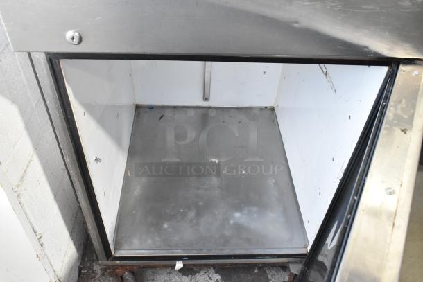 True TA1R-2HS commercial cooler interior, two half-size doors, on casters. Metal and white interior, 115V, some wear visible.