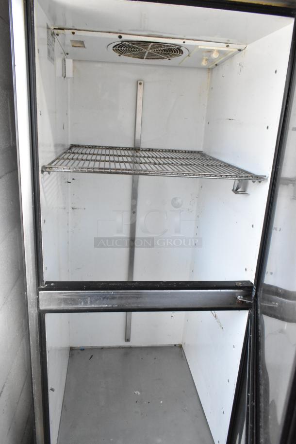 True TA1R-2HS commercial reach-in cooler with 2 half-size doors, wire shelf, and fan. Mounted on casters, 115V, 1 phase.