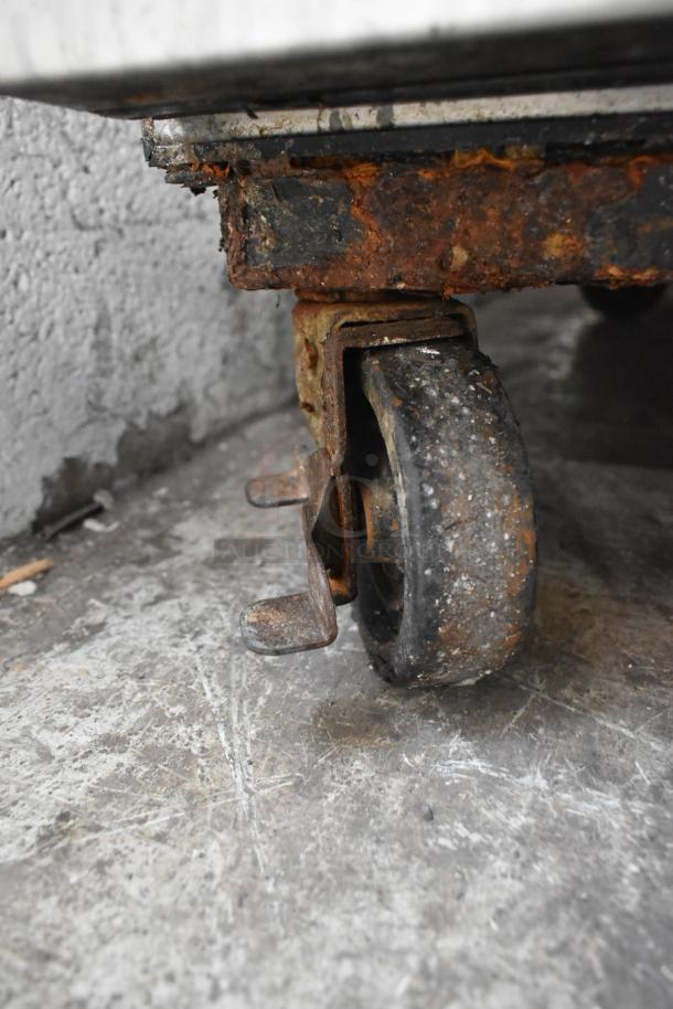 Close-up of a rusted commercial caster on the True TA1R-2HS cooler.