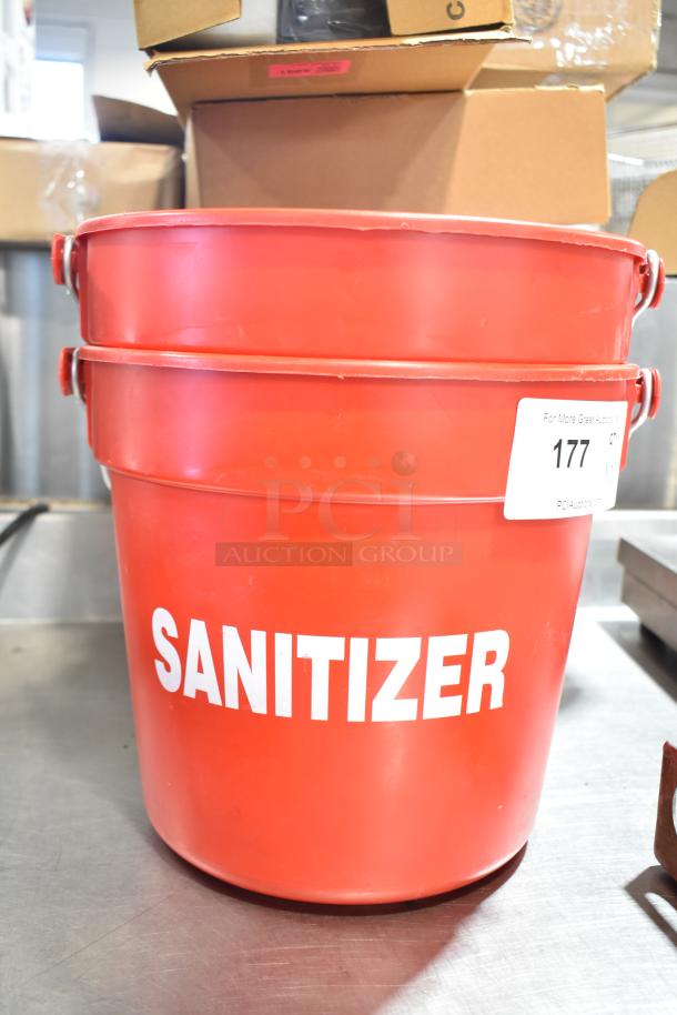 Two red poly buckets labeled "SANITIZER," stackable design, auction lot number 177 tag visible, clean condition.