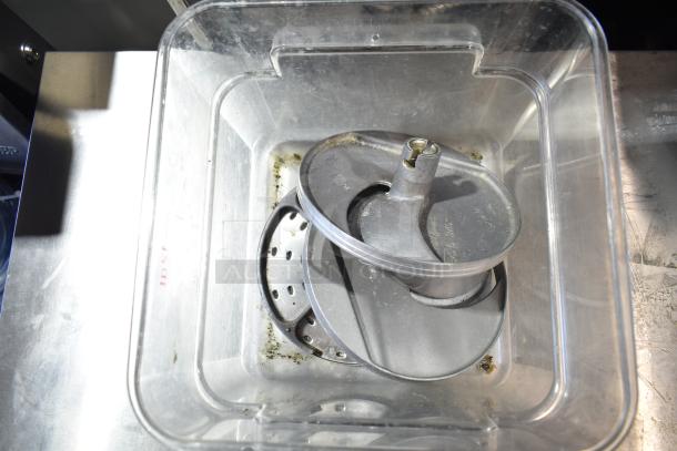 Clear poly bin with Lancer power supply and three food processor blades, slightly used, visible tarnish inside bin.