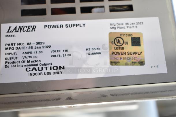 Lancer power supply with labels, MFG date 26 Jan 2022, in clear poly bin with 3 food processor blades included.