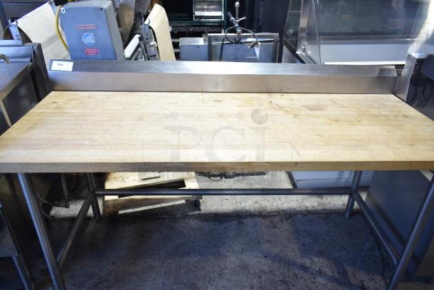 Butcher block table with wooden top and metal frame; surface shows signs of use, highlighting durability.