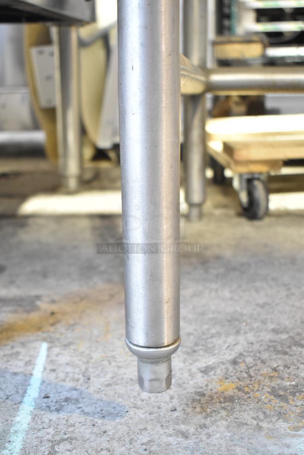 Stainless steel leg of a butcher block table, showing wear. The surface is slightly scratched, indicating use.