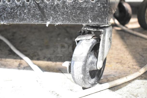 Turbo Air TOM-50B-N caster detail, showing dust and wear, part of a 50" vertical open air merchandiser.