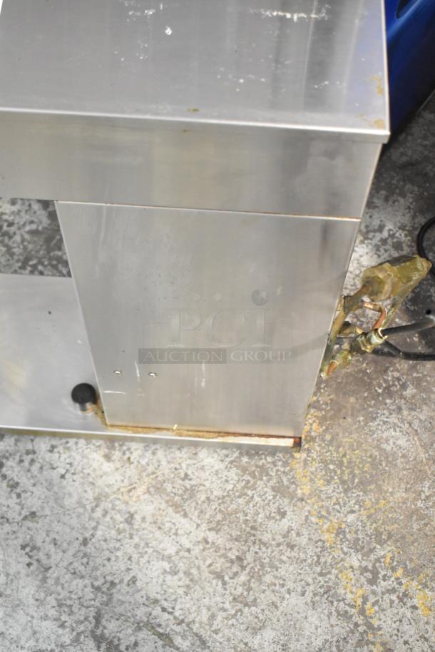 Stainless steel countertop coffee machine with hot water dispenser, some wear visible. No brand markings visible.