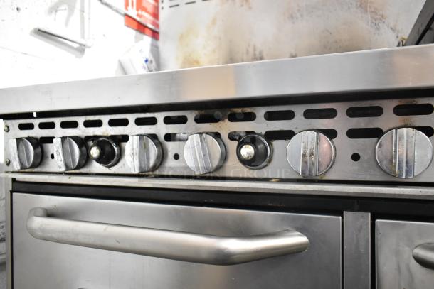 Bakers Pride commercial gas range with 6 burners, flat top griddle, cheese melter, 2 ovens, and backsplash. Used condition.