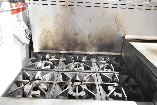 Bakers Pride 6-burner gas range with flat top griddle, cheese melter, 2 ovens, and backsplash; shows signs of use.