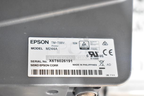 Epson receipt printer model M244A, shown with label displaying model, serial number X6T6026191, and manufacturing details.