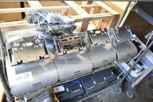 Five Micros Oracle POS docking stations on a metal shelf, good condition, visible auction tags with item numbers "226" and "227".