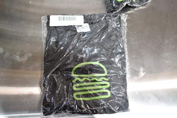 9 brand new scratch and dent unisex Steff tees in packaging. Includes 2X size. Features a green burger logo and barcode label.
