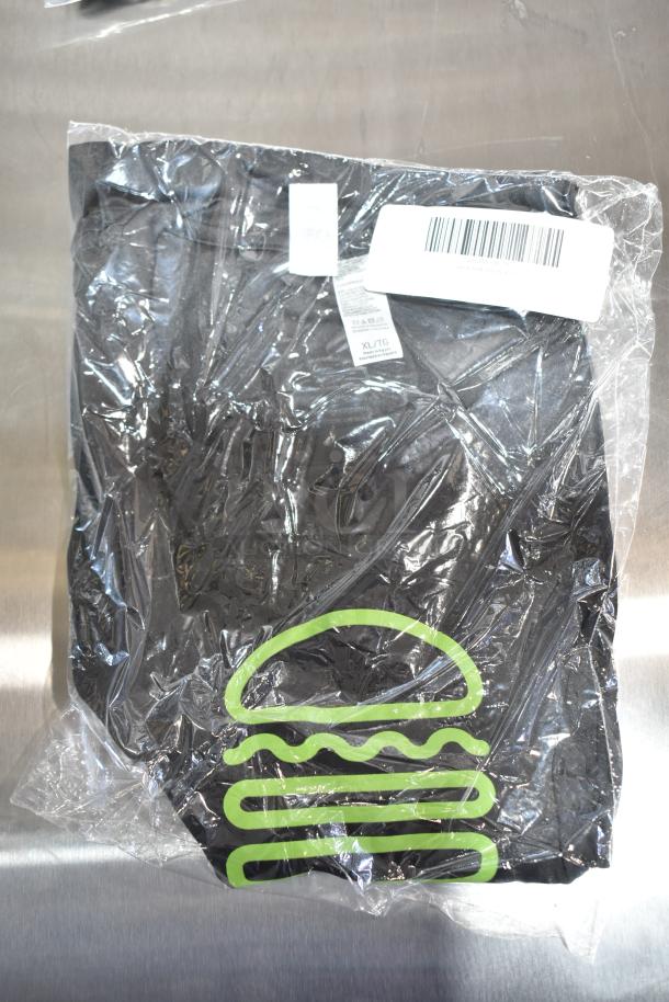 Packaged black unisex Steff tee, brand new with tags, size XL/2X, showing a green graphic design.