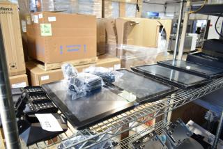 10 items including 4 POS monitors and 3 Ingenico credit card readers on a metal shelf. Boxes in background.