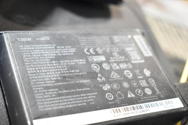 Label close-up of a Lenovo 135W AC adapter model ADL135SCC3A highlighting safety and manufacturing details.