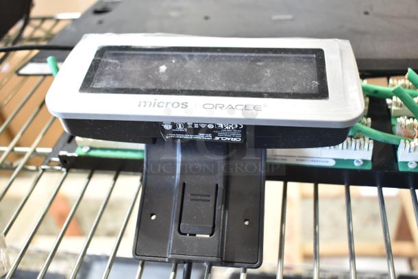 Oracle Micros cash drawer display with visible branding mounted on a black bracket on a shelf.