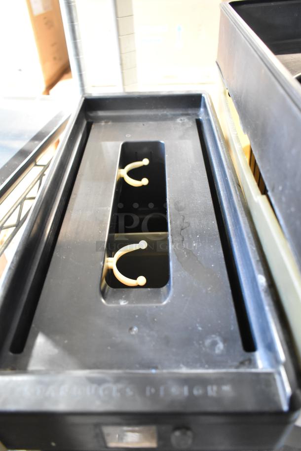 Black storage bin with dividers and openings, labeled "Starbucks Design," in good condition.