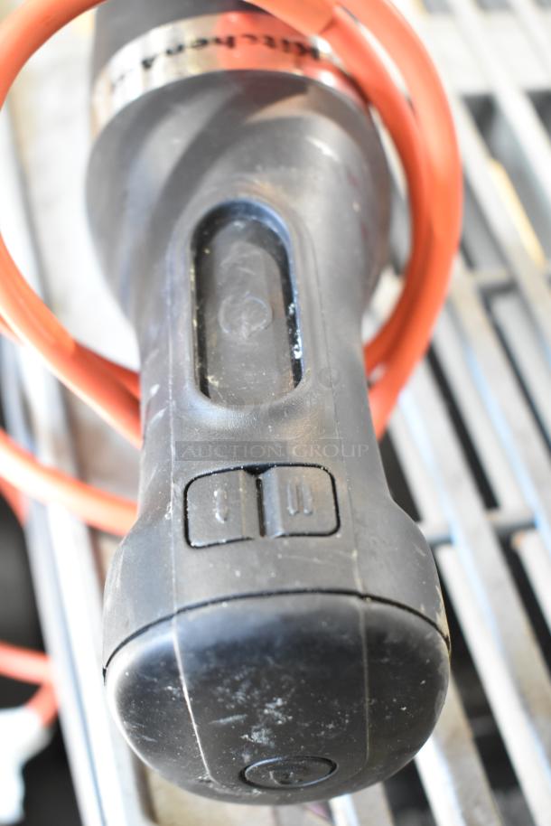 Black immersion blender handle, no blade, 115 volts, 1 phase, visible wear, red cord attached.