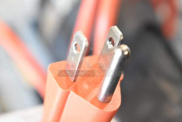 Red plastic plug of an immersion blender, no blade included. Features 115 volts, 1 phase. Close-up view of prongs.