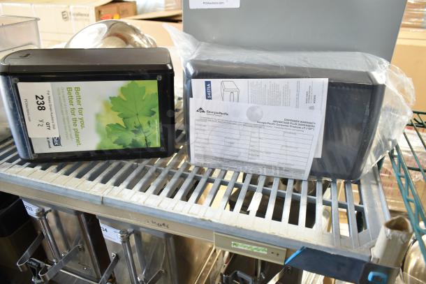 Two Georgia-Pacific countertop napkin dispensers, black, with warranty documents. One with an eco-friendly label. Excellent condition.
