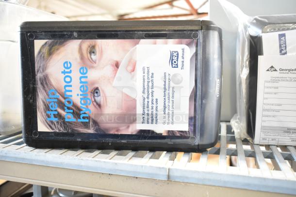 Tork Xpressnap countertop napkin dispensers, black, promotional hygiene message, includes branding and usage instructions.