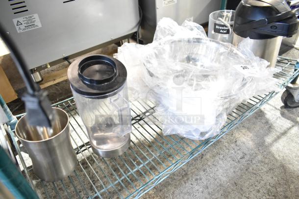 Various kitchen items including a blender pitcher, metal cup, and bowls on a shelf. Some items wrapped in plastic. Label indicates "Strawberry Acai."