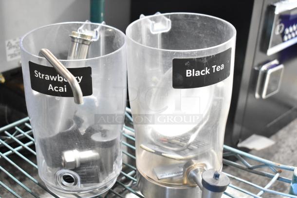 Set of two clear dispensers labeled "Strawberry Acai" and "Black Tea" on a wire shelf with metal fixtures inside.