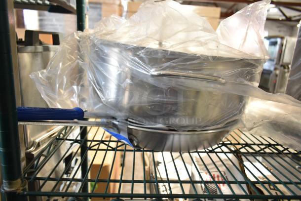 Four assorted items, featuring a Vollrath CeramiGuard II Wear Ever Fry Pan. New, wrapped in plastic, on metal shelving.