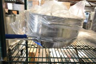 Four assorted items, featuring a Vollrath CeramiGuard II Wear Ever Fry Pan. New, wrapped in plastic, on metal shelving.