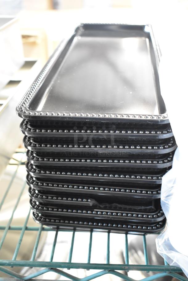 Stack of black poly trays with beaded edges, part of a lot with poly insulated bins and Cambro containers.