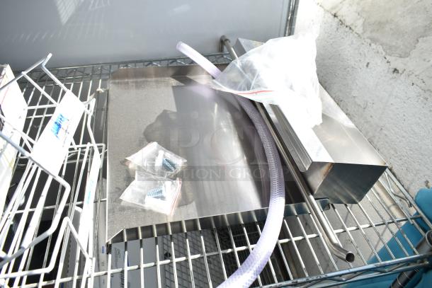 Six brand new scratch and dent items, including metal pieces and a white wire rack, displayed on a metal shelf.