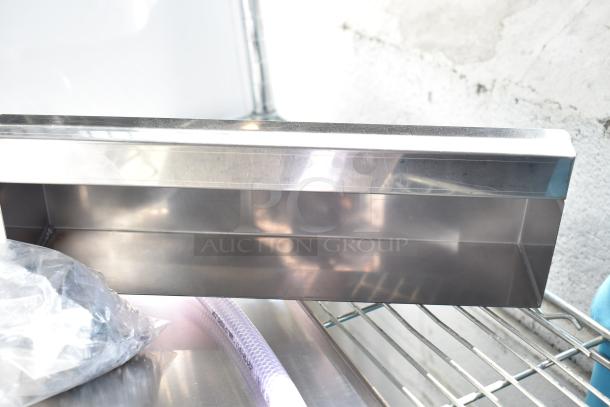 Six new scratch and dent metal pieces including a white rack, showcasing their shiny finish. Perfect for bidding.