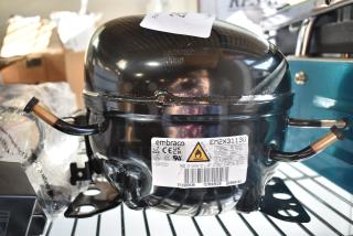 Brand new Embraco EM2X3113U compressor, compatible with multiple Avantco models, 115V, R290, with tags visible.