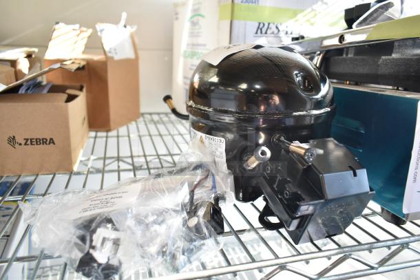 BRAND NEW Embraco EM2X3113U Compressor, scratch and dent, for Avantco AU-27R-HC series, 115V, R290, on metal shelf.