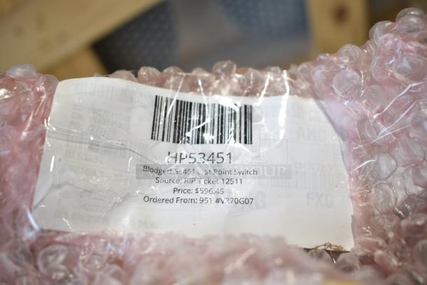 Box of assorted items including a Berkel blade, point switch, and ignition control, labeled with barcode and price tag.