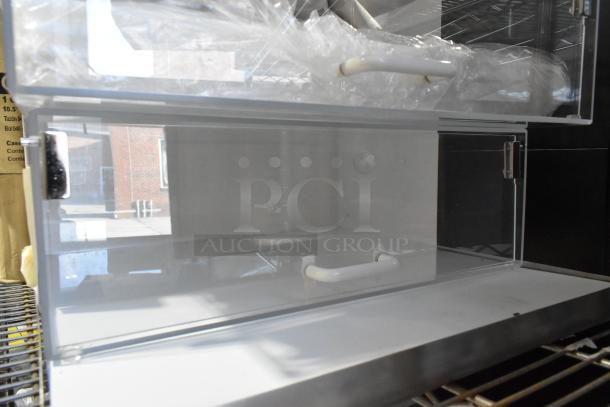 Brand new countertop dry display case merchandiser, clear acrylic with handles, minor scratches and dents visible.