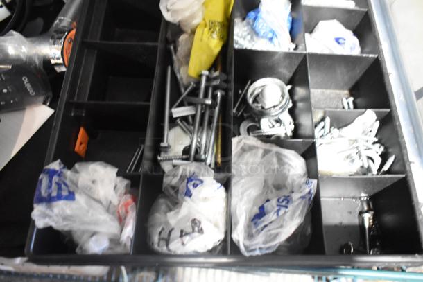 Organized toolbox with assorted fasteners, screws, and hardware in compartments. Includes bags and metal parts. Good condition.