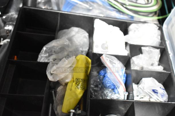 Black toolbox with multiple compartments containing various tools, screws, and hardware items in plastic bags.