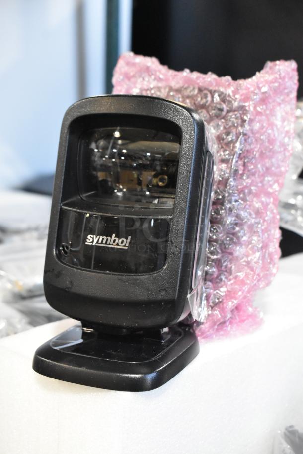 Symbol barcode scanner, black, with brand logo visible, packaged in pink bubble wrap, part of 10-item auction lot.