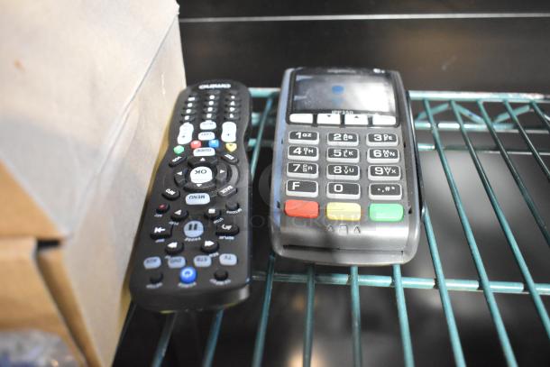 Assorted tech items including remote and credit card reader on metal shelf. Used condition. Auction lot of 10 varied items.