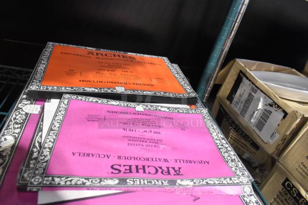 Stacks of Arches watercolor pads in orange and pink, 23x31 cm, 20 sheets each, 300 gsm.